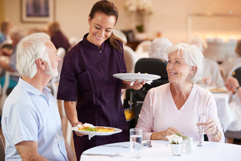 Elderly Couple Getting Served Dinner at Senior Living Facility Elderly Couple Getting Served Dinner at Senior Living Facility