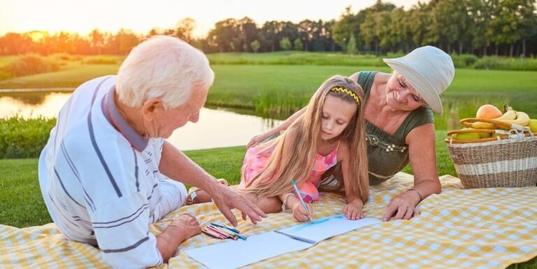 Grandparents Enjoying Outdoor Picnic with Granddaughter at Assisted Living Facility