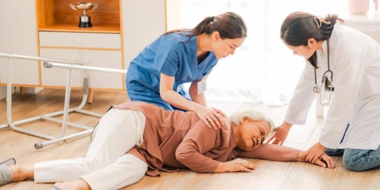 Two Skilled Nurses Leading Emergency Training Drill With Elderly Resident At Assisted Living Facility