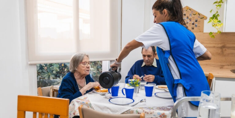 Female Nurse Serving Breakfast to Resident at Assisted Living Facility
